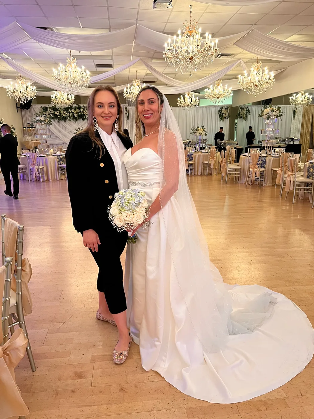Bride with a loved one beneath the chandeliers